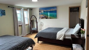 A bedroom with two beds, a large window with curtains, a mirror, a painting of a coastal scene, and a wooden floor. - Charming 4-bedroom house with WiFi and AC in beautiful Niagara Falls (Niagara Falls)