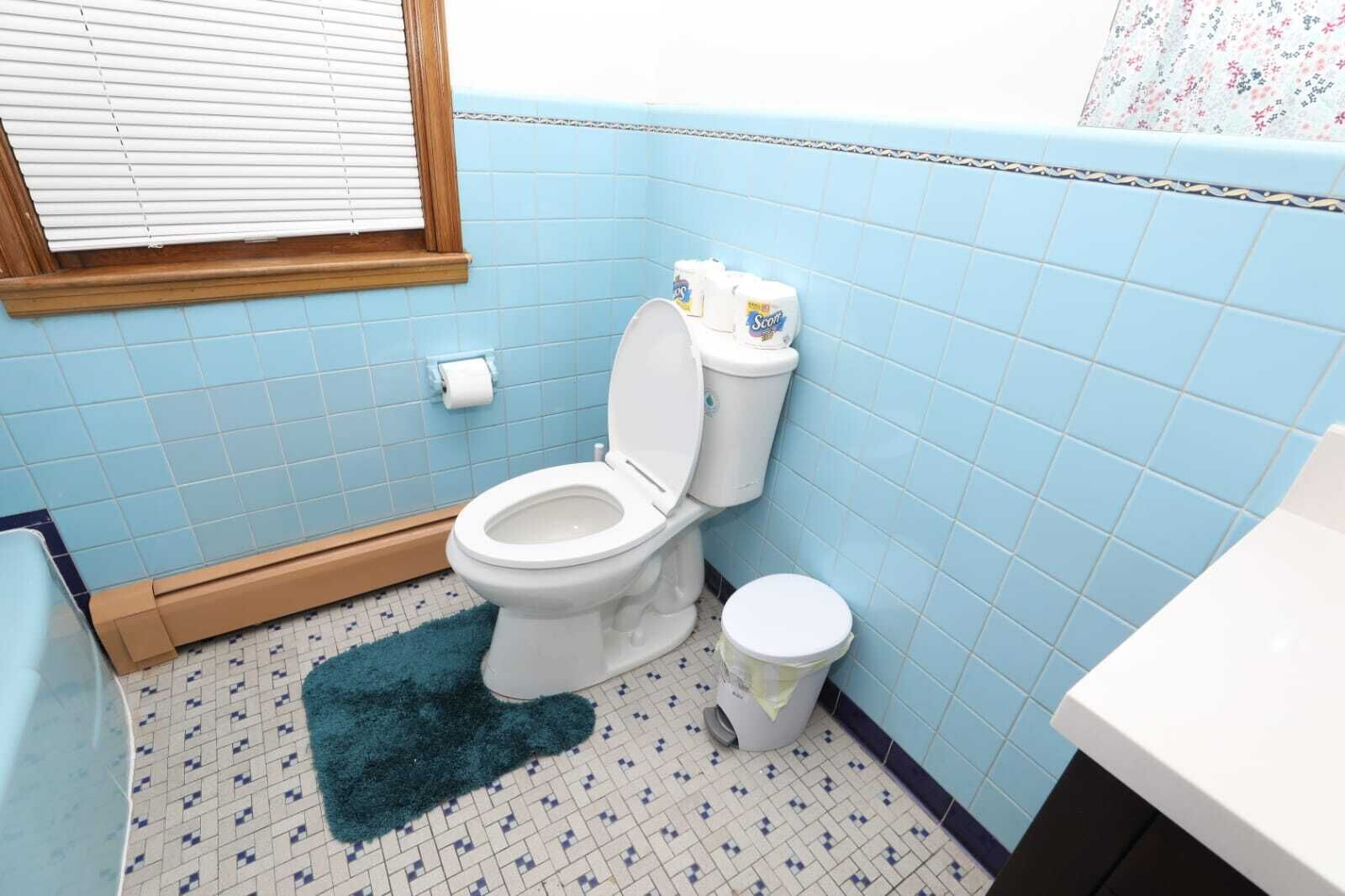Un baño con inodoro, bidé y una pequeña alfombra en el suelo.