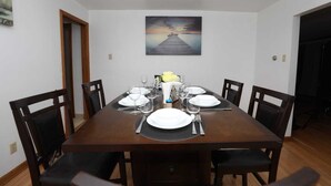 A dining room with a wooden table set for six, surrounded by six chairs. - Charming 4-bedroom house with WiFi and AC in beautiful Niagara Falls (Niagara Falls)
