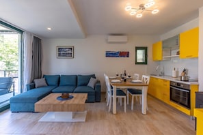 A modern living room with a sectional sofa, dining table, and yellow kitchen cabinets. - Beachside House Lara, Omišalj, Croatia (Omišalj)