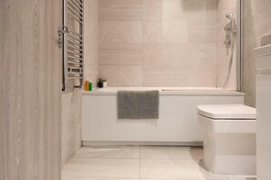 Bathroom features a bathtub, toilet, and shower area with a handheld showerhead.