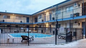 Un motel à plusieurs étages doté d’une piscine, d’un espace clôturé et d’un panneau indiquant l’emplacement de la piscine.