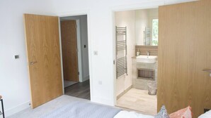 Un dormitorio moderno con una cama grande, un armario de madera y un baño con lavamanos y toallero.