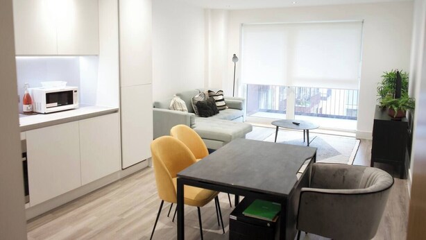 Un apartamento moderno con cocina, comedor y sala de estar. Incluye un sofá, una mesa de centro y un mueble para televisión.