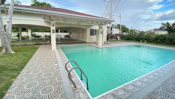 Una piscina con plataforma de azulejos y zona cubierta con techo rojo.
