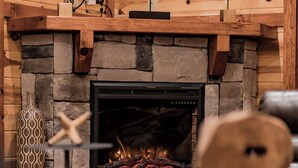 A stone fireplace with a modern design, a decorative vase, and a log fire. - Fabulous Mountain views,4-bedroom cabin, Indoor Heated Pool, Hot Tub, Media Room (Sevierville)