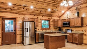 A kitchen with wooden walls, a central island, stainless steel appliances, and a window. - Fabulous Mountain views,4-bedroom cabin, Indoor Heated Pool, Hot Tub, Media Room (Sevierville)