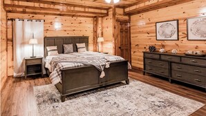 A wooden cabin bedroom with a bed, nightstands, a dresser, and a ceiling fan. - Fabulous Mountain views,4-bedroom cabin, Indoor Heated Pool, Hot Tub, Media Room (Sevierville)