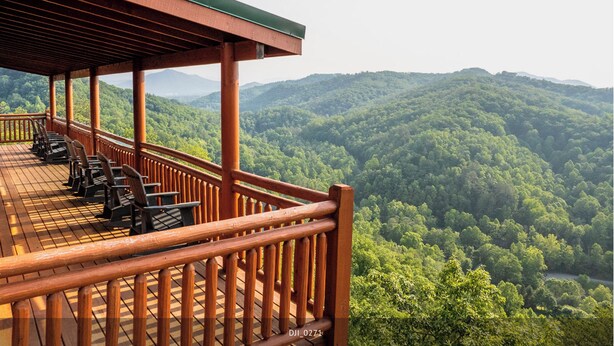 A wooden deck with chairs overlooking a forested valley. - Fabulous Mountain views,4-bedroom cabin, Indoor Heated Pool, Hot Tub, Media Room (Sevierville)