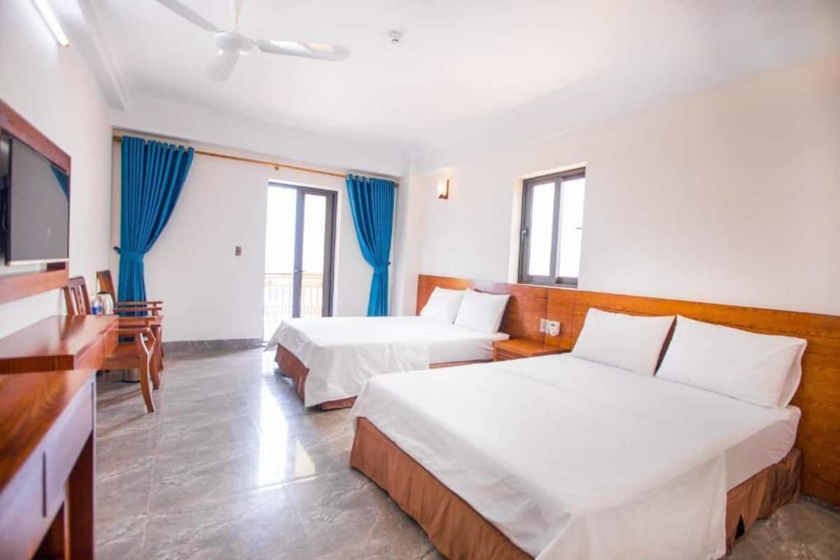 A hotel room with two beds, a TV, a desk, and a chair.