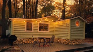A log cabin with a deck, a table with chairs, and string lights.