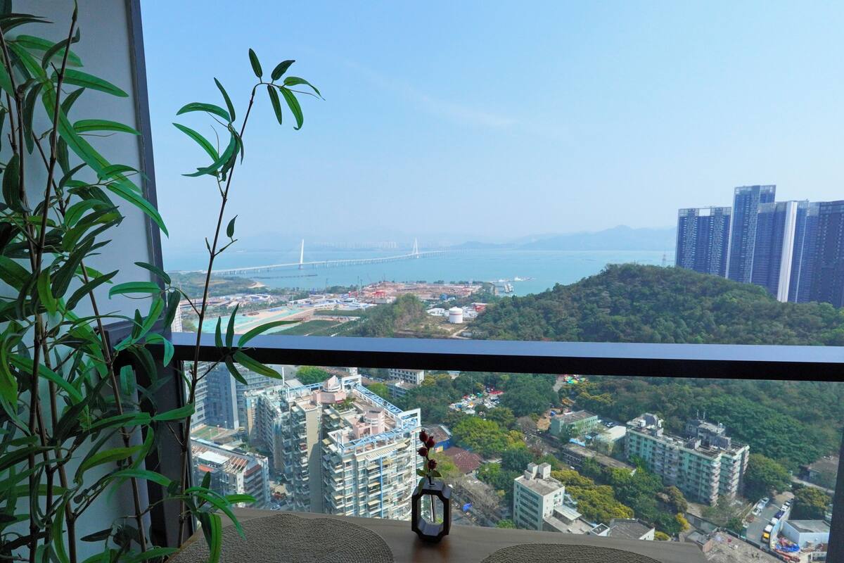 A balcony with a view of a cityscape, including buildings and a bridge.