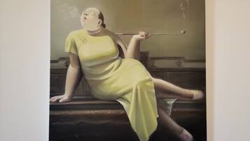 Una pintura de una persona con un vestido amarillo sentada en un banco.