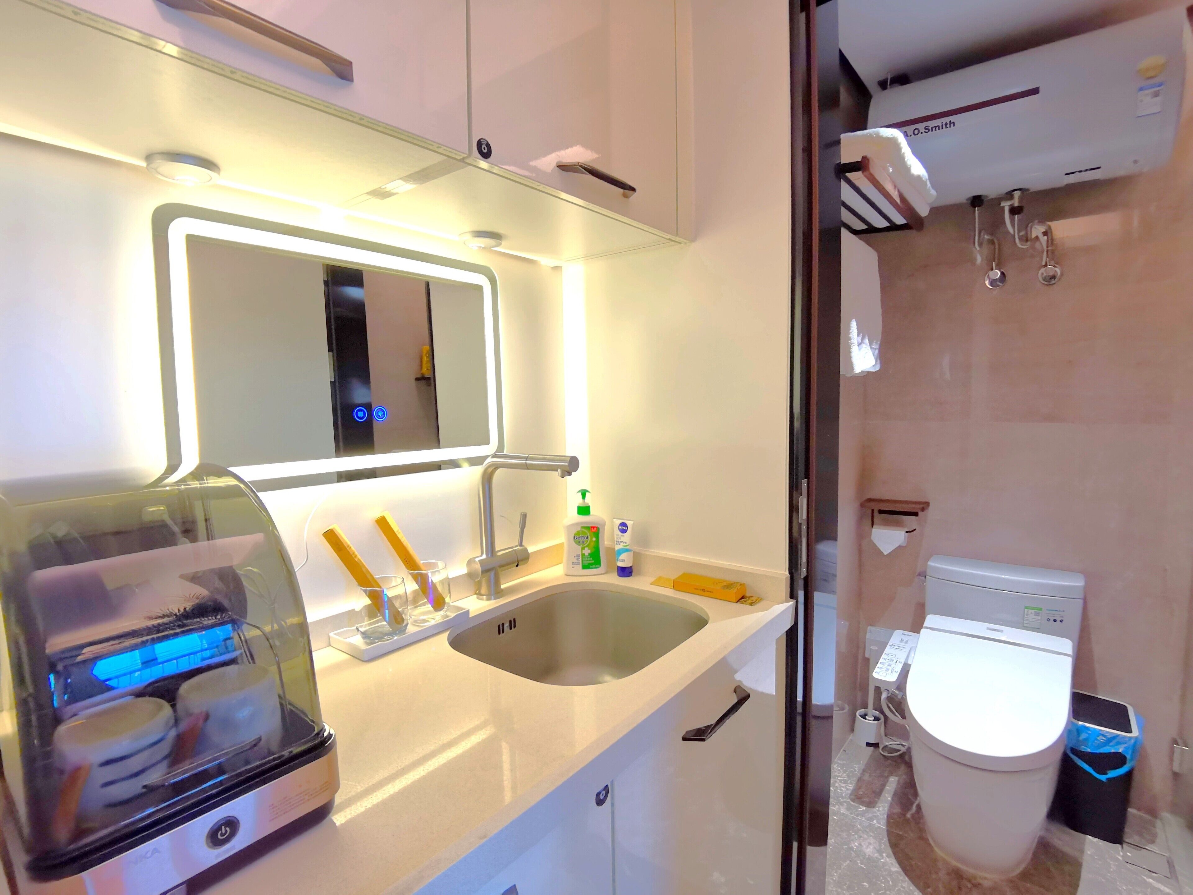 A modern bathroom with a sink, mirror, and a toilet.