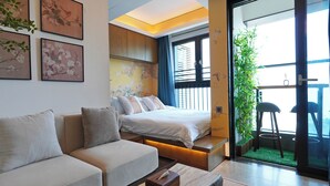 Una habitación de hotel moderna con sofá, cama, una mesita de madera y un balcón con vistas.