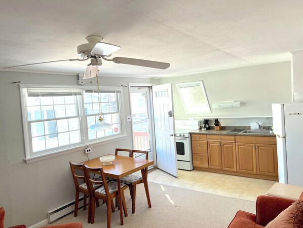 A compact kitchen with wooden cabinets, a white refrigerator, and a dining area with a table and chairs.