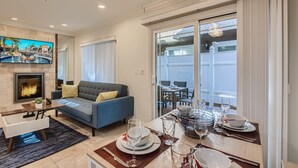 Una sala de estar moderna con chimenea, un sofá, una mesa de comedor para cuatro personas y un balcón con vistas.