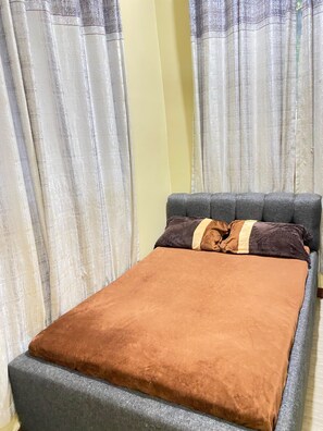 A bed with a grey headboard and a brown blanket.