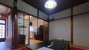Una habitación con piso de madera, una mesa negra con una carta, un banco rojo y una puerta corredera que da a una zona de cocina.
