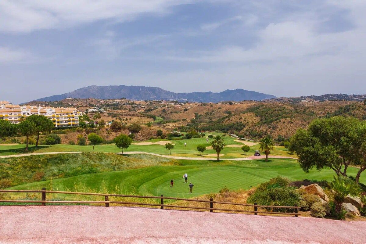 Ein Golfplatz mit Blick auf Berge und eine Wohngegend im Hintergrund.