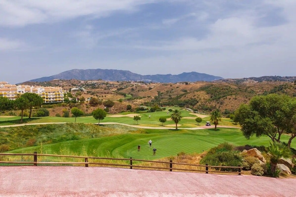 A golf course with a view of mountains and a residential area in the background.