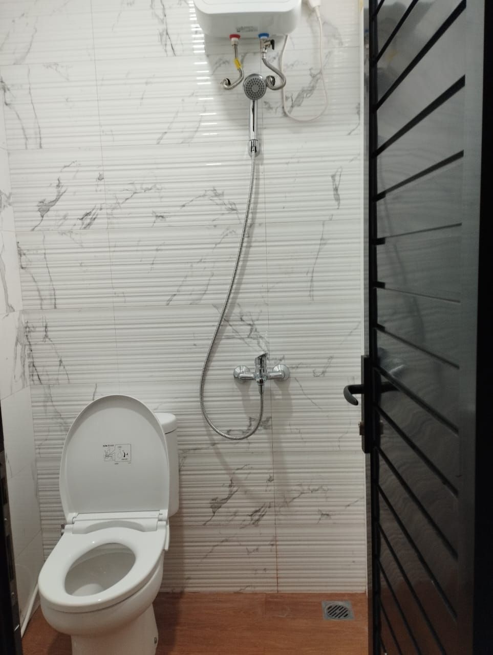 A bathroom with a toilet, a shower, and a sink.