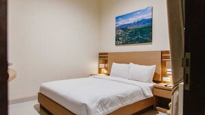 A neatly made bed with white linens in a hotel room. - Musafir Guest House Syariah (Surakarta)