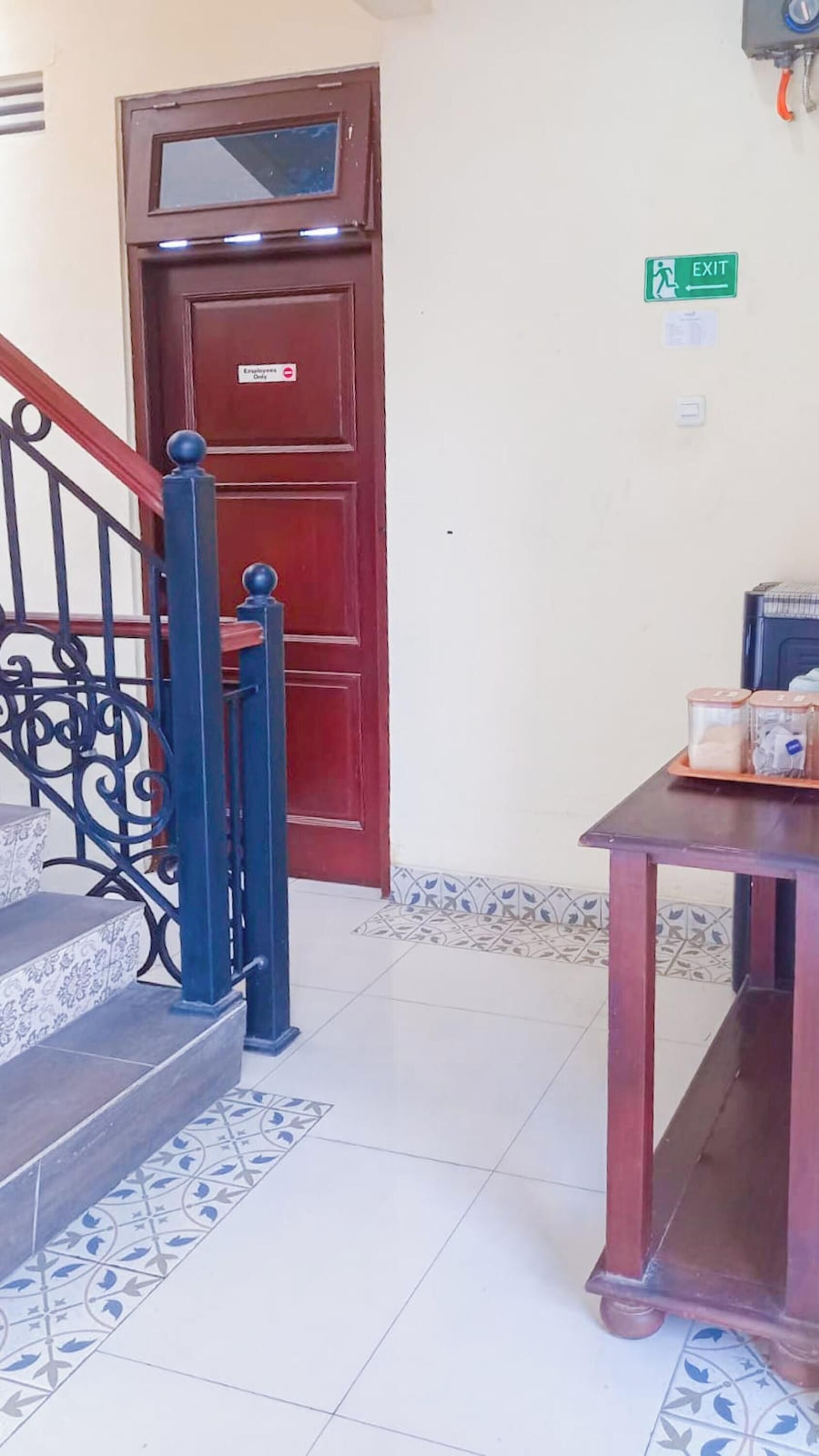 A staircase with a red door marked "Employee Only" and an exit sign on the wall.