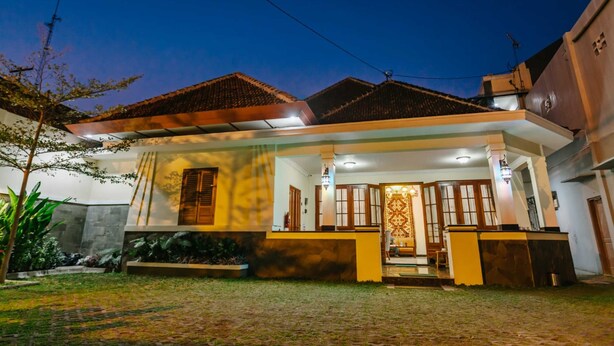 A modern house with a well-maintained garden, a large porch, and a traditional tiled roof. - Musafir Guest House Syariah (Surakarta)