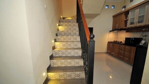 A staircase with patterned tiles leading to a kitchen area with wooden cabinets and a black countertop. - Musafir Guest House Syariah (Surakarta)