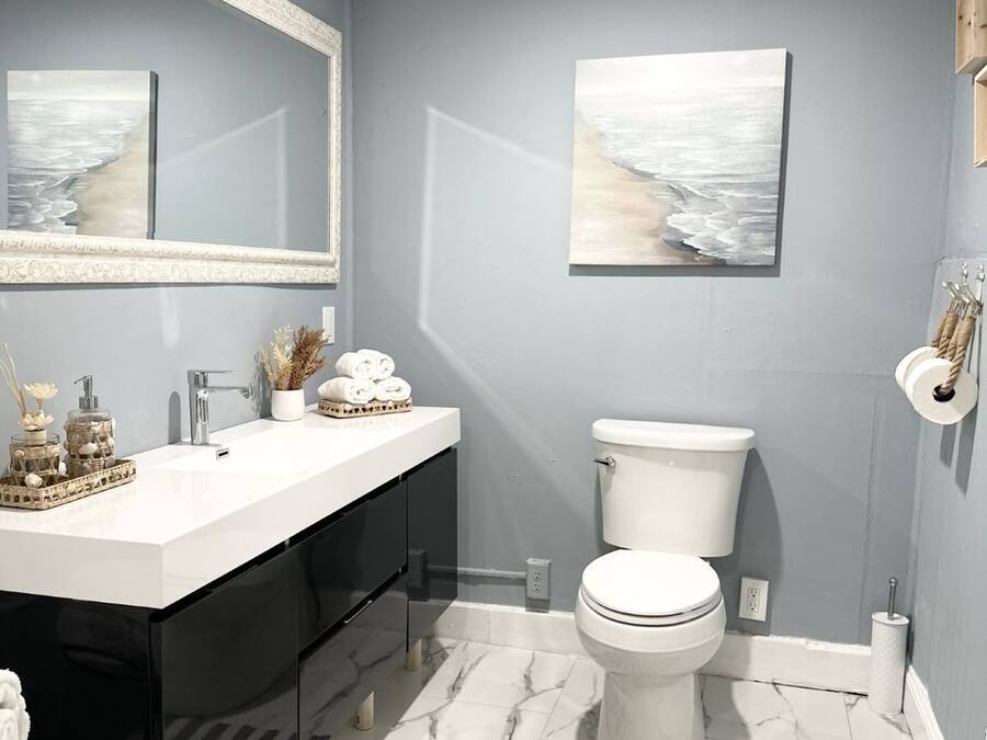 Un baño moderno con un tocador blanco, un inodoro y un espejo grande.