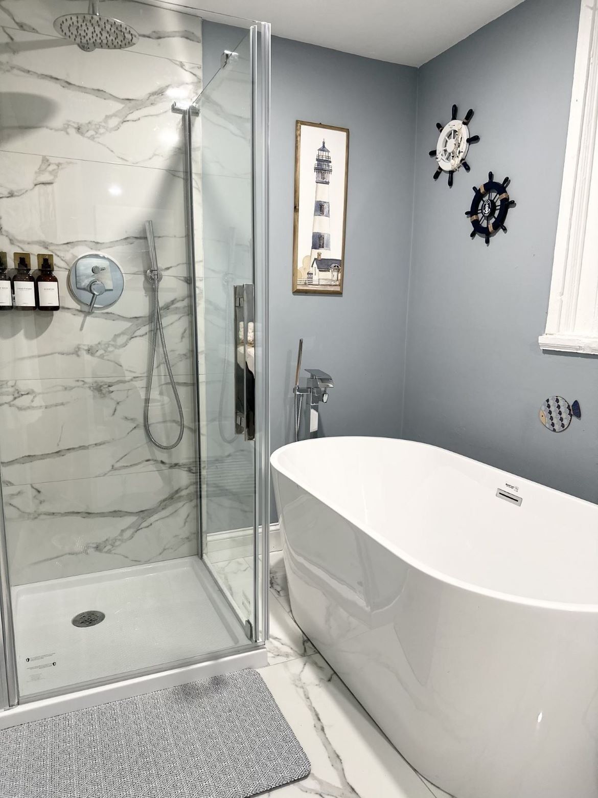 A modern bathroom with a glass-enclosed shower, a freestanding bathtub, and a marble backsplash.