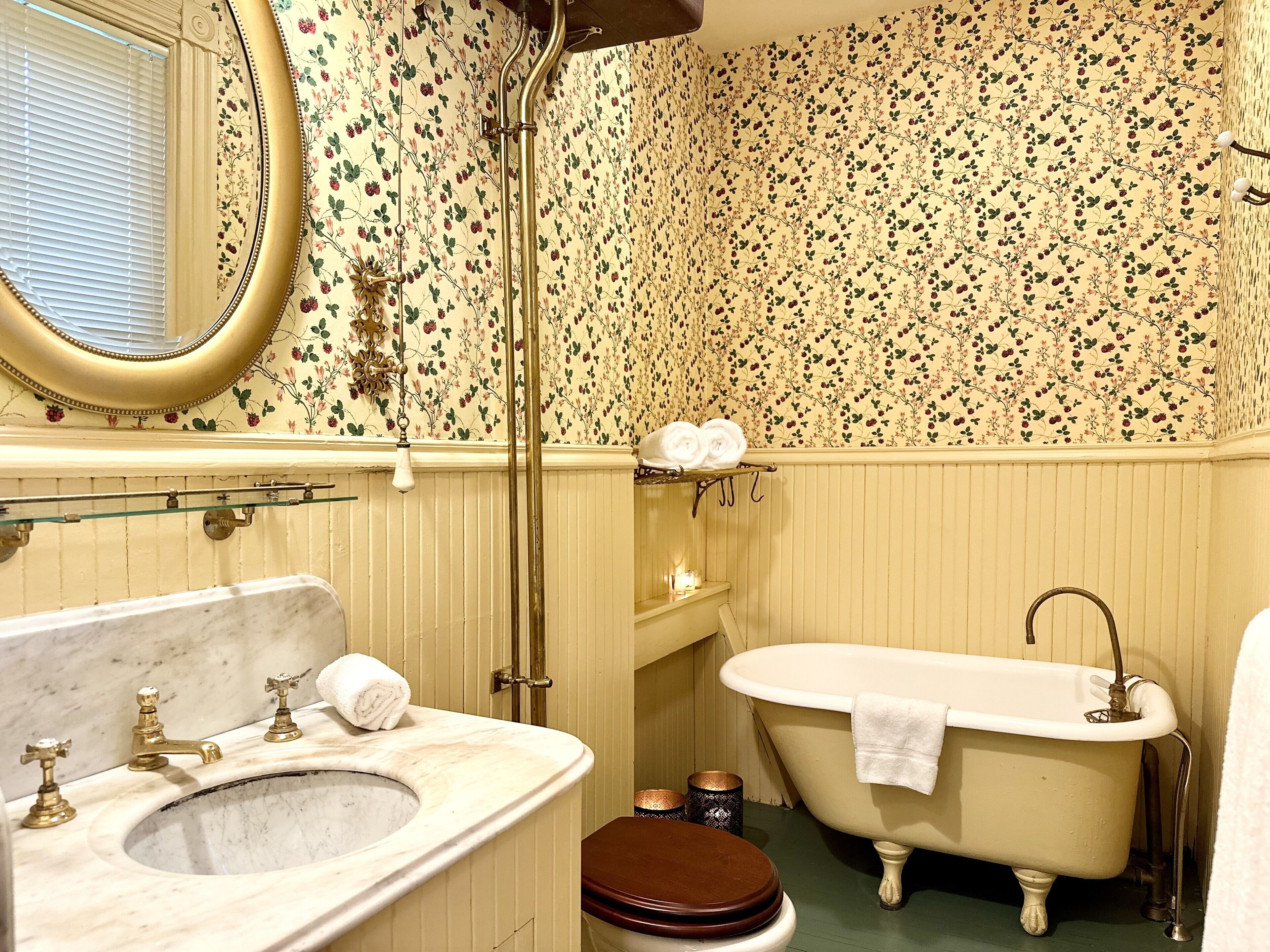 Un baño de estilo vintage, que incluye una bañera de patas de león, un lavabo clásico y un inodoro.