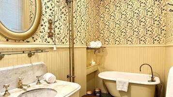 Un baño de estilo vintage, que incluye una bañera de patas de león, un lavabo clásico y un inodoro.