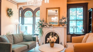 Un salon chaleureux avec une cheminée, un canapé, une table basse ronde et un lustre.