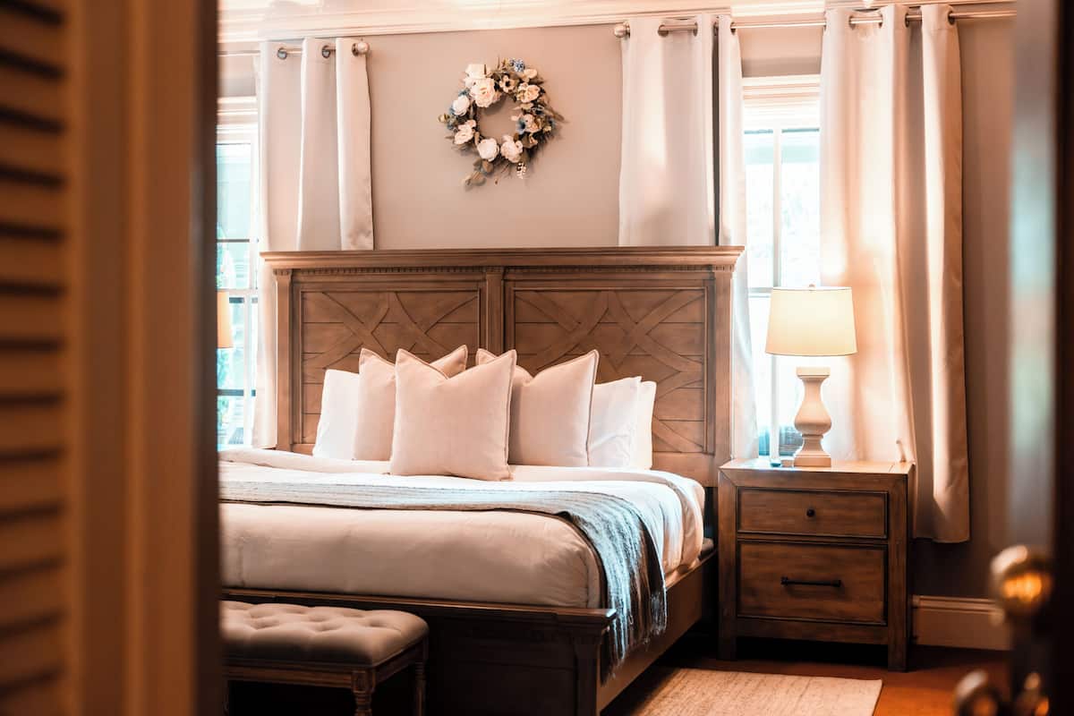 A bedroom with a bed, a nightstand, a lamp, and a wall-mounted decorative wreath.
