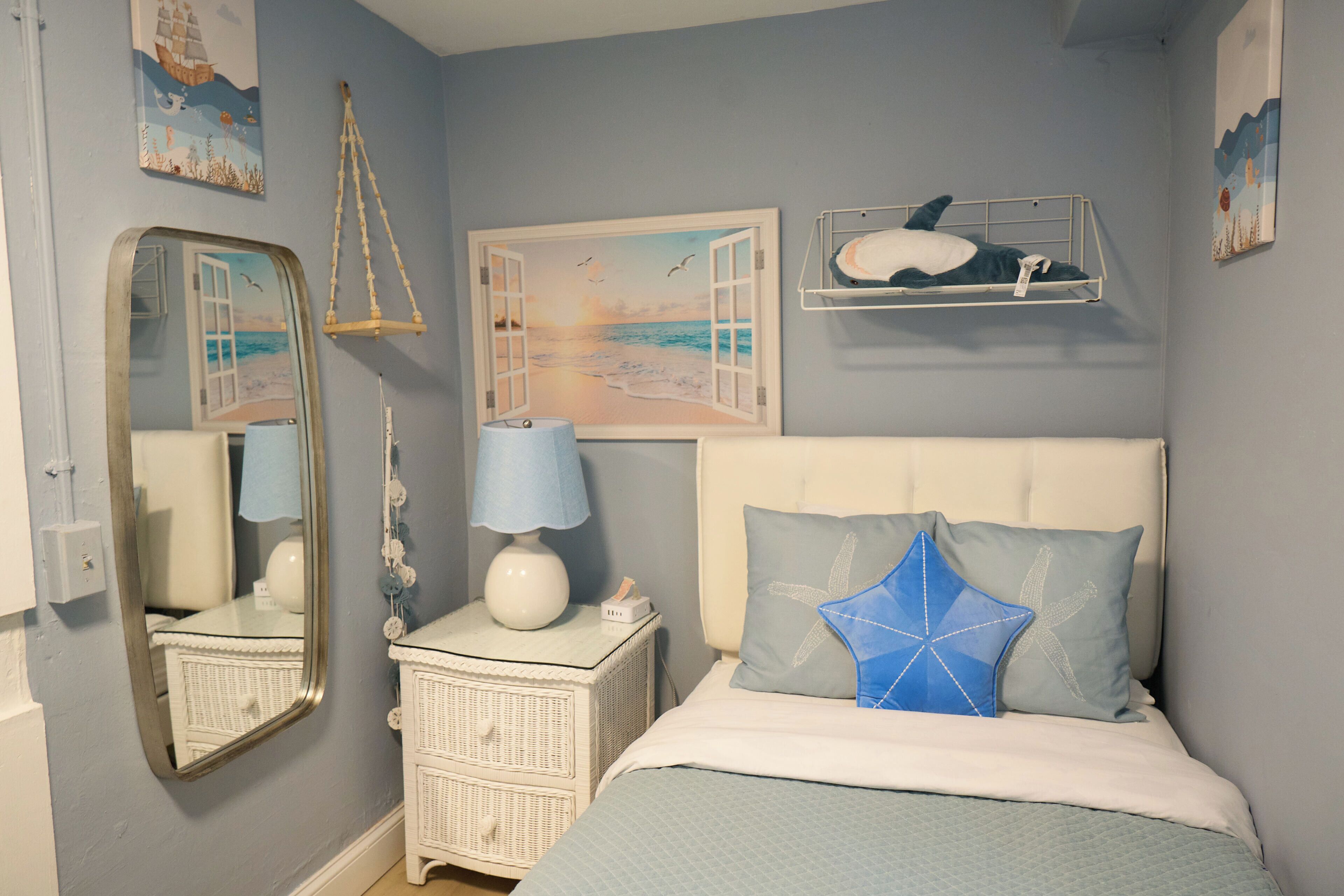 Ein Schlafzimmer mit Bett, Nachttisch, Kommode, Spiegel und Wandbildern.