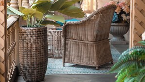 Une véranda aménagée avec des meubles en osier et des plantes en pot.