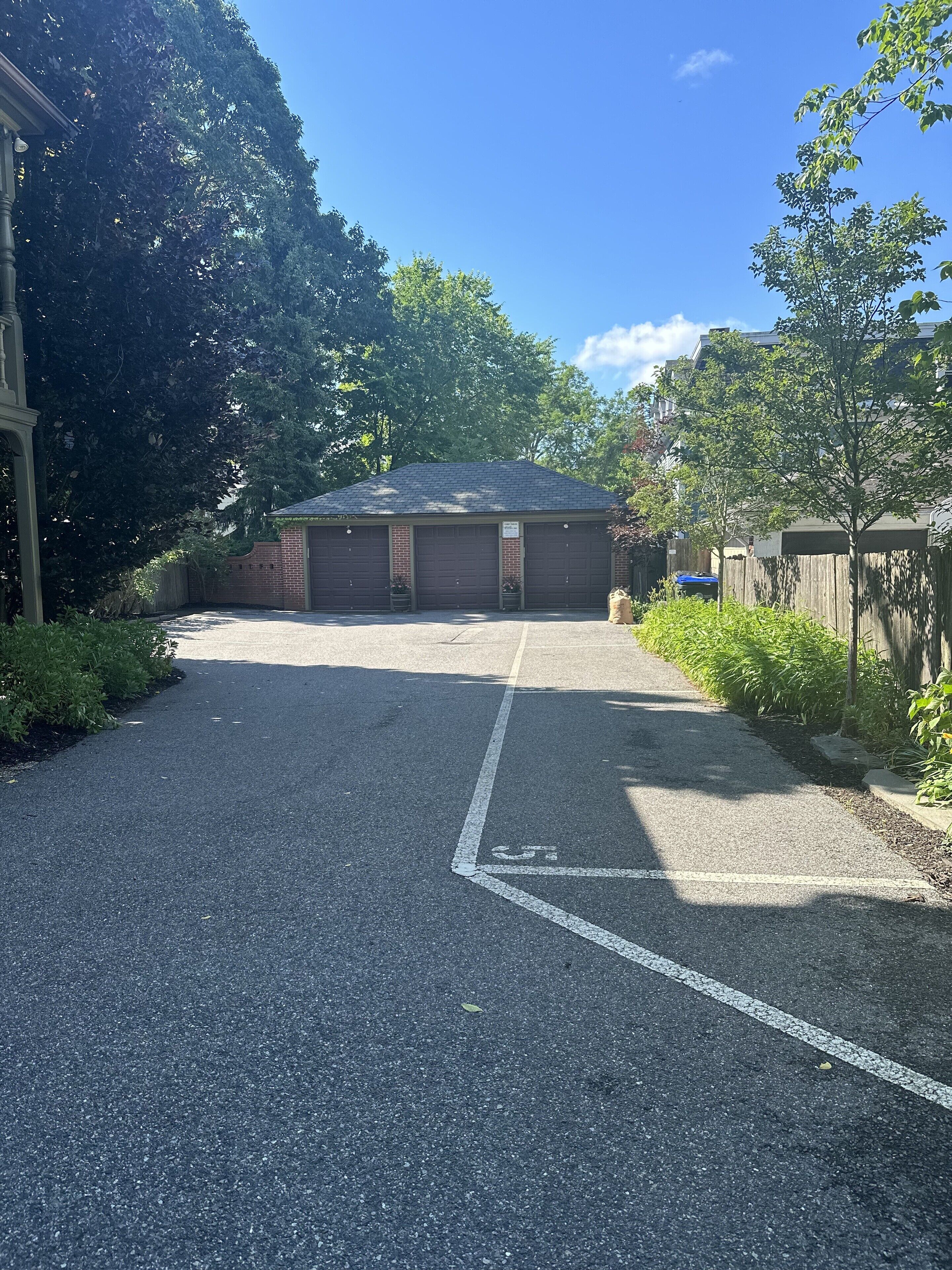 A parking garage with two open garage doors, surrounded by trees and a clear sky.
