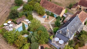 Vista aerea di una proprietà residenziale con piscina, diverse case e vegetazione circostante.