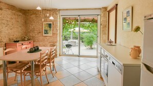 Una cucina con zona pranzo, pareti in pietra e vista sul giardino tramite una porta vetrata.