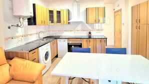 Una cocina compacta con comedor, lavadora y sofá.