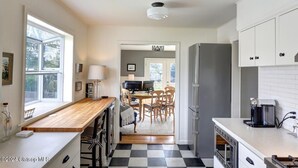 A kitchen with a wooden countertop, a refrigerator, and a dining area with chairs and a table. - 3 Bedroom Beach Oasis - HOT TUB - Pet Friendly (Seaside)