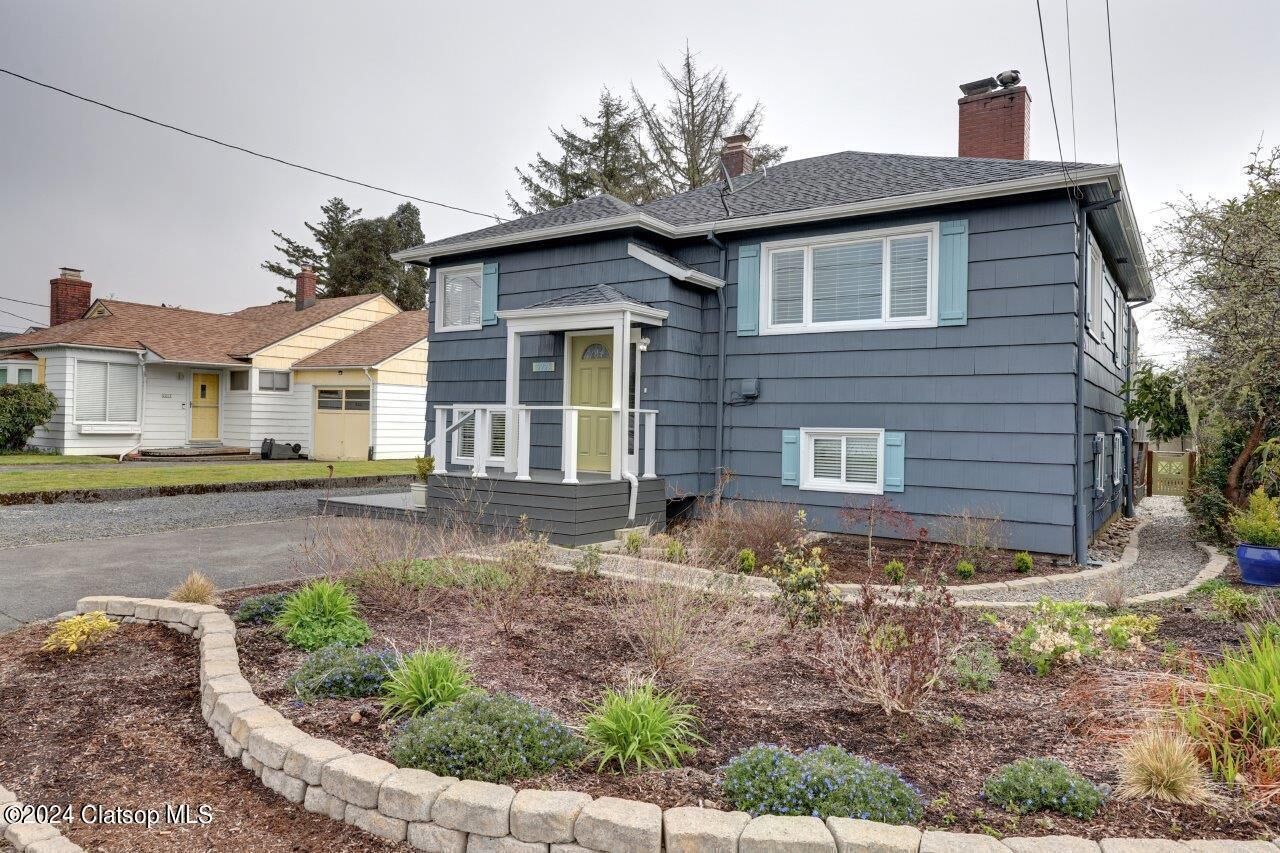 A two-story house with a front porch and a landscaped garden.