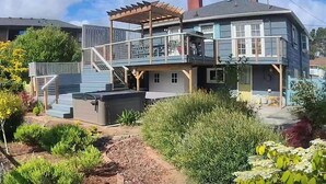 A two-story house with a covered patio, a visible staircase, and a garden area. - 3 Bedroom Beach Oasis - HOT TUB - Pet Friendly (Seaside)