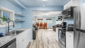 Una cocina moderna con electrodomésticos de acero inoxidable, encimera de mármol y pared de color azul claro.