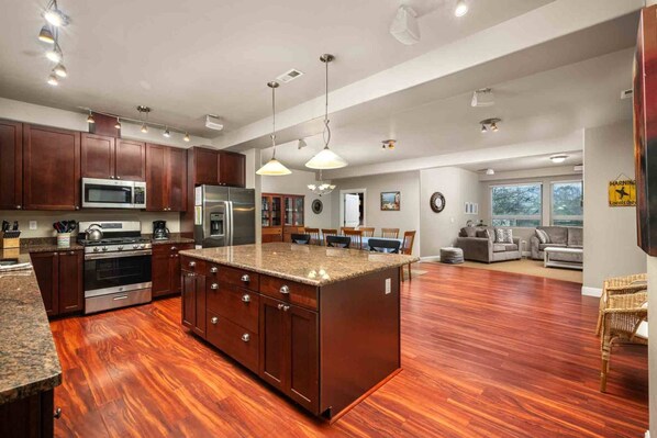 A spacious kitchen with dark wood cabinets, stainless steel appliances, and a large island.