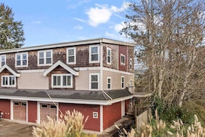 A two-story building with a red and beige exterior, multiple windows, and a garage. - Incredible Riverside Escape, Five Blocks to Ocean, Hot Tub, Ping Pong, Foosball (Seaside)