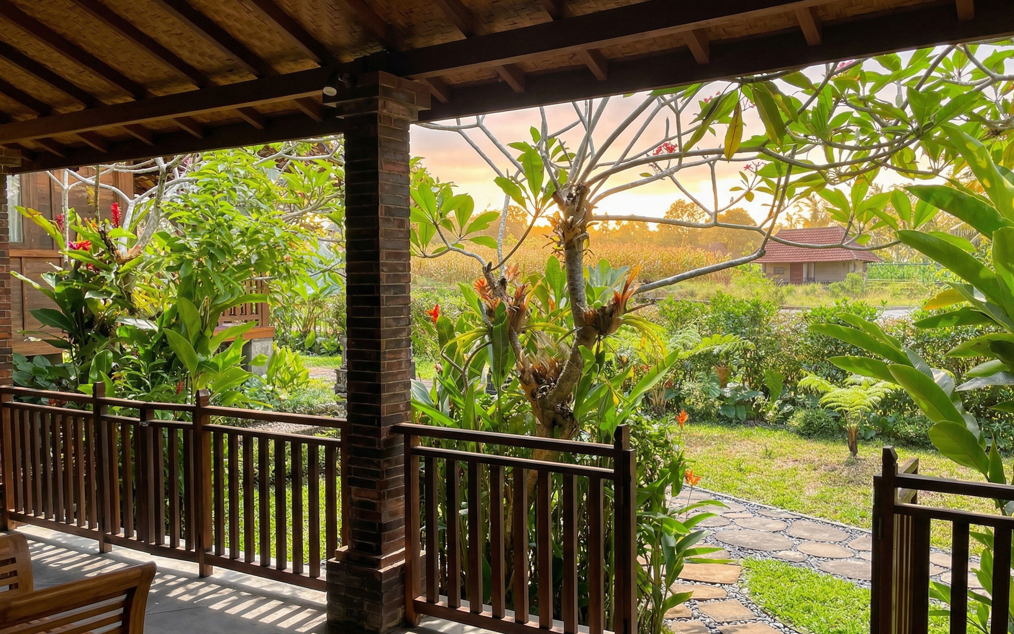 A covered outdoor area with a wooden bench, a stone pathway, and lush greenery.
