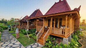 A wooden house with a tiled roof, a porch, and a staircase leading to the entrance. - Sirya Farm House (Tabanan)